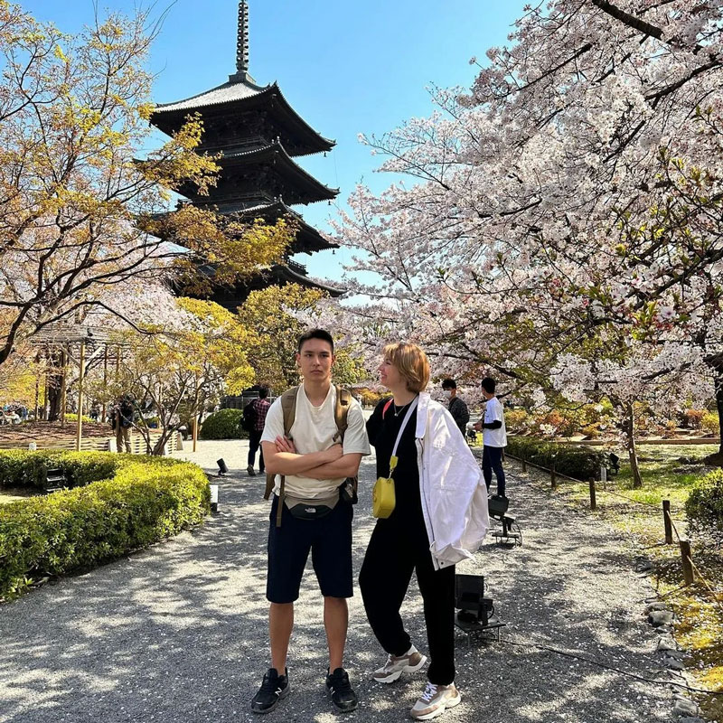 Orijinal haliyle, Japonya’daki tapınak önünde duran çift ve arka planda kablolar, ışıklar ve insanlar.