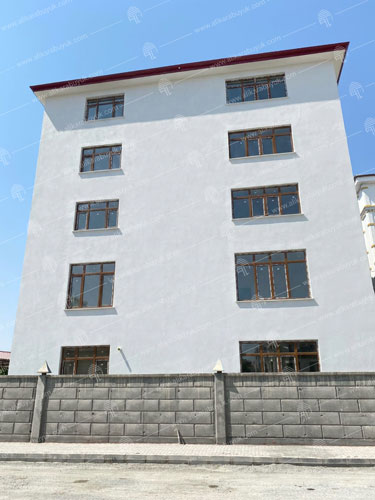 Sıva uygulanmış, kireç boyalı cepheye sahip ve camları düzeltilmiş bina